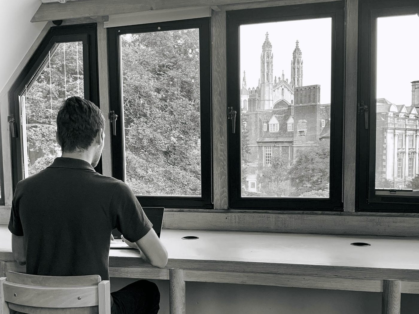 Jason working at a laptop in the Jerwood Library at Trinity Hall, with King’s College Chapel in the distance