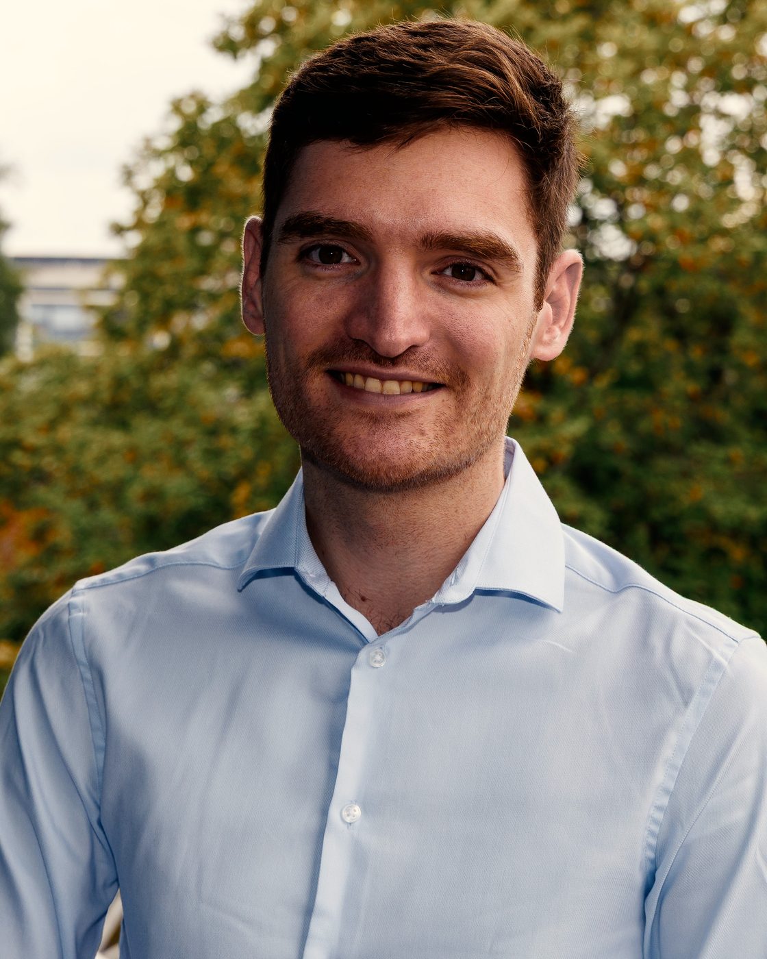 Jason Mashinchi, head and shoulders, smiling, with trees behind